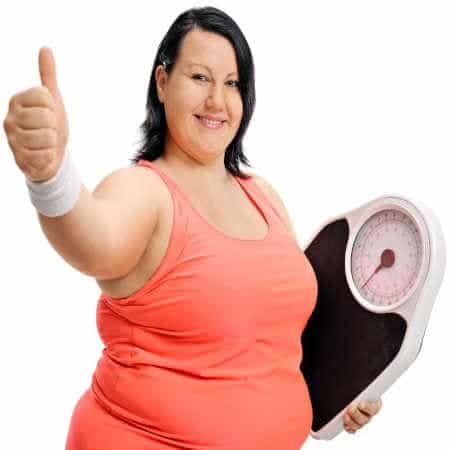 Übergewicht ohne viel Essen Frau hält mit Stolz eine Waage in der Hand